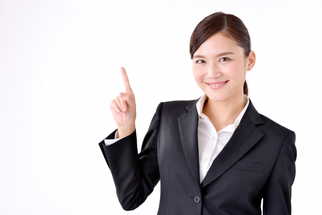 スーツ姿の女性が人差し指を立てて微笑んでいる画像