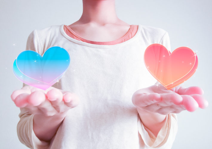 手のひらに乗ったハートを差し出している女性