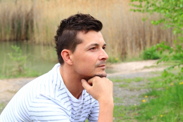 顎に手をついて遠くを見ている外国人男性の横顔