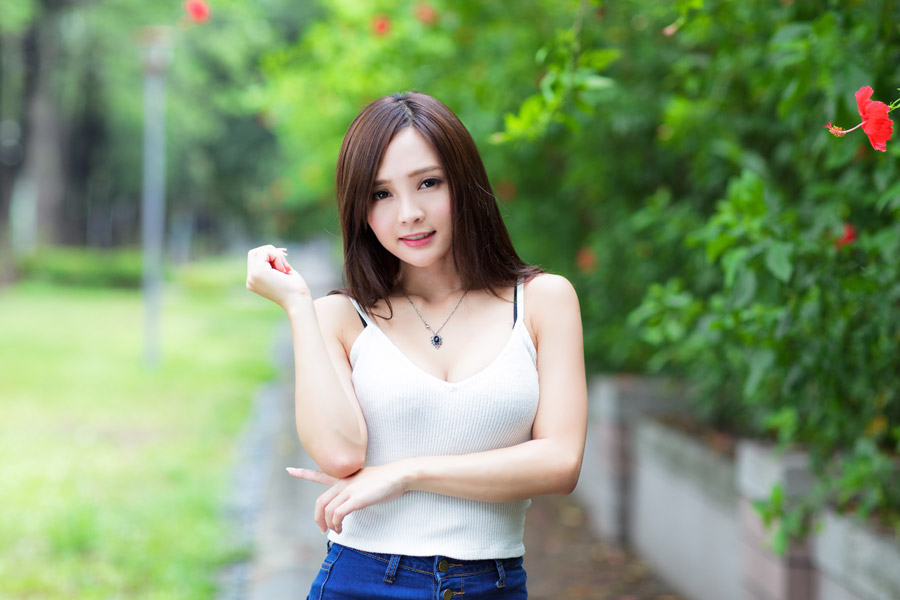 白いキャミソールをきたロングヘアの日本人女性