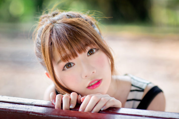 ベンチの背もたれから顔を覗かせている女性