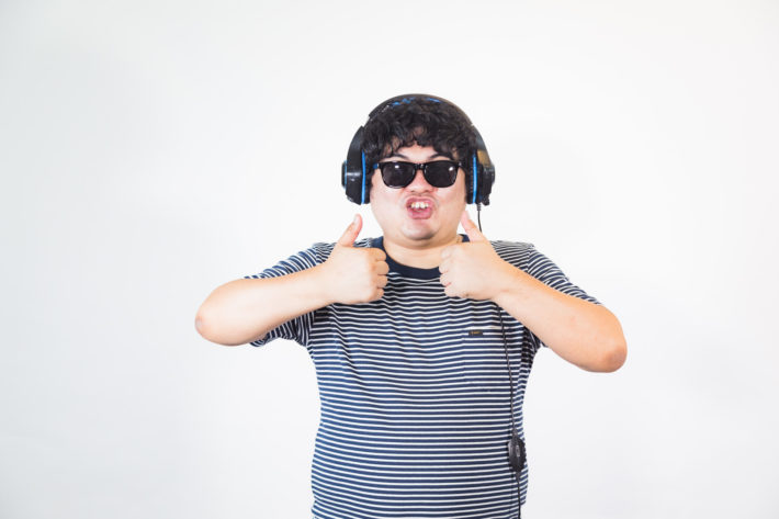 サングラスとヘッドホンをした太った男性が両親指を立てている画像