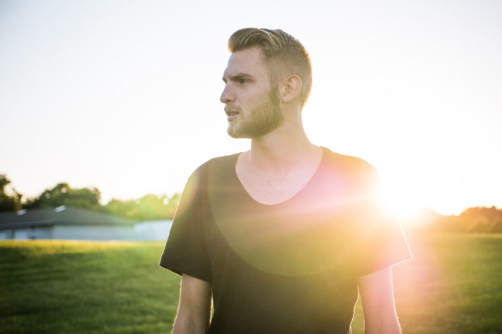 野原でどこか遠くを見つめている男性の横顔