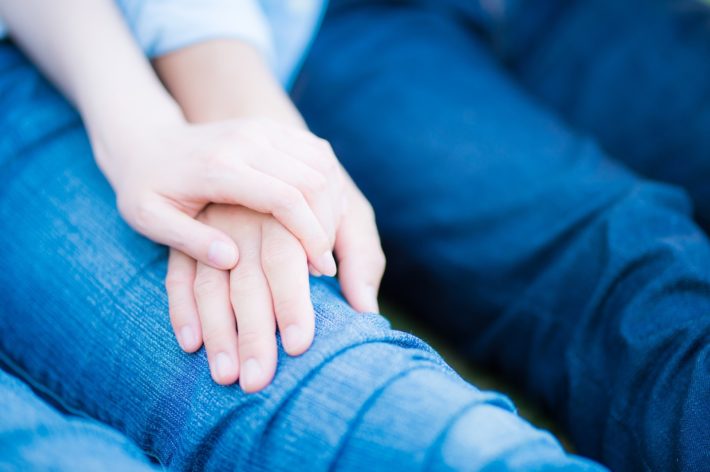 膝の上で手を重ね合っている男女