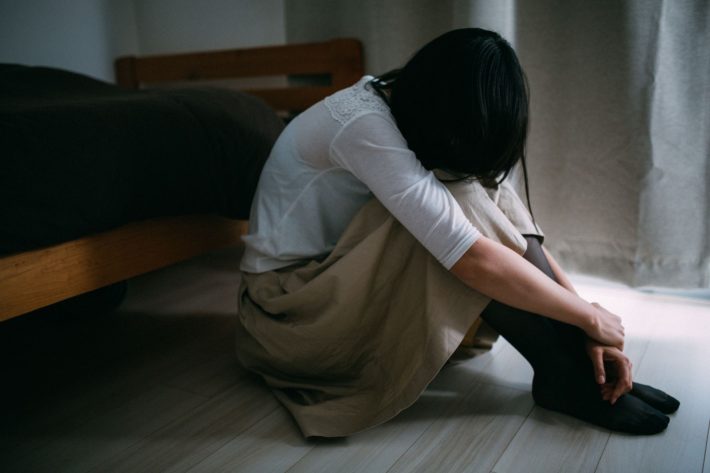 膝を抱えている女性