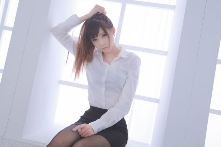 窓辺に座り髪をかきあげている女性