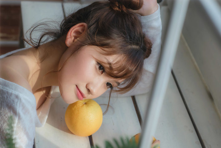 オレンジの上に顔を乗せている女性