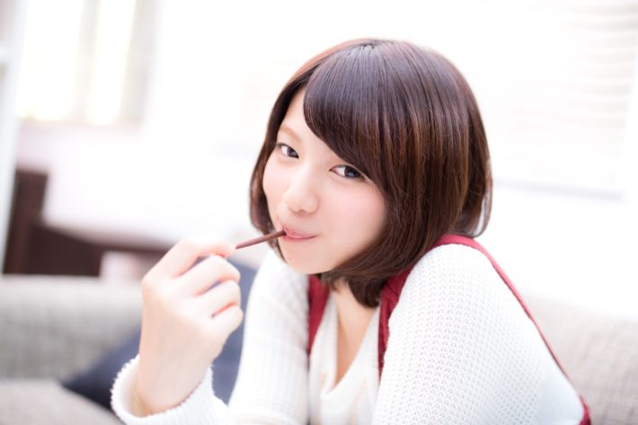 ポッキーを口に咥えほほ笑んでいる女性