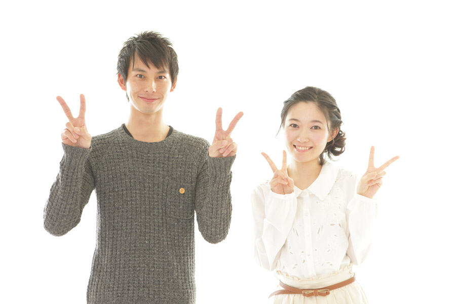 両手でピースサインをしている男女のカップル