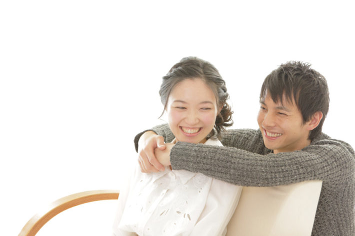 ソファーの後ろから女性を抱きしめる男性