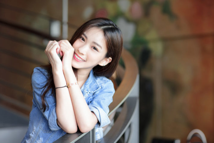 手すりに肘をついて微笑む女性