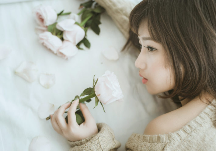 バラの花を持ちうつ伏せになっている女性