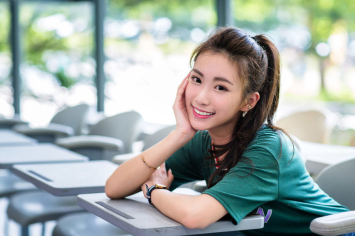 教室で頬杖をつきこちらに微笑む女性