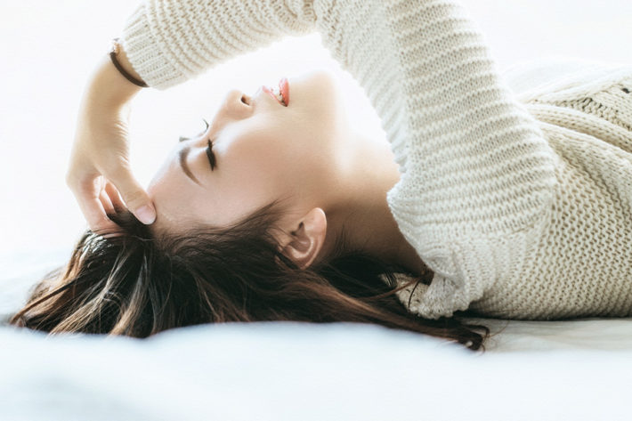 仰向けに寝転んで考え事をしている女性