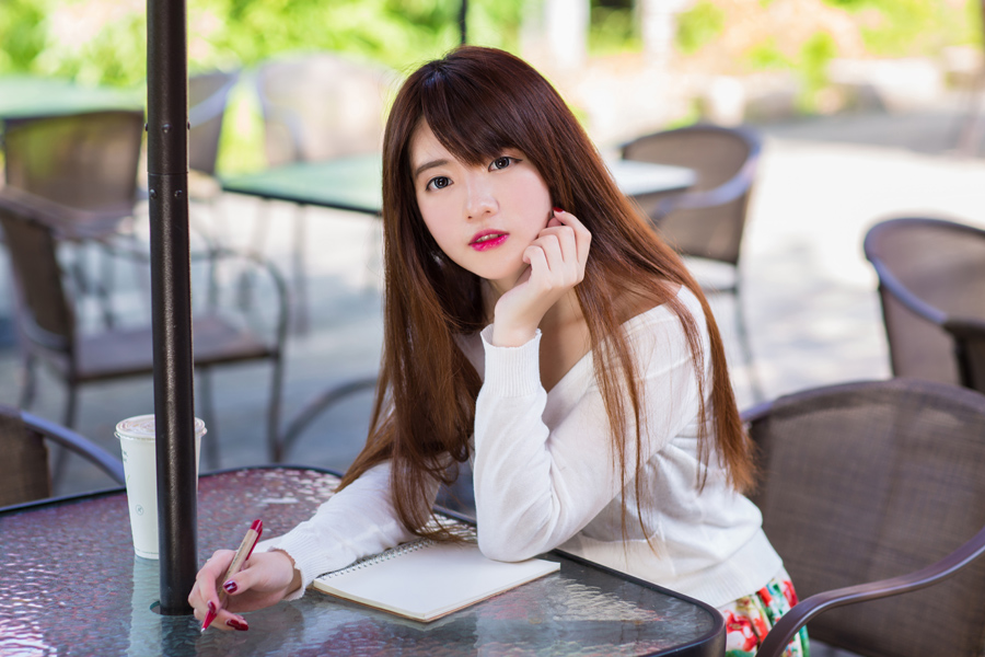 ノートを開き頬杖をついてこちらを見ている女性