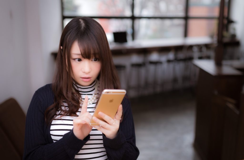 驚いた表情でスマホを使う女性
