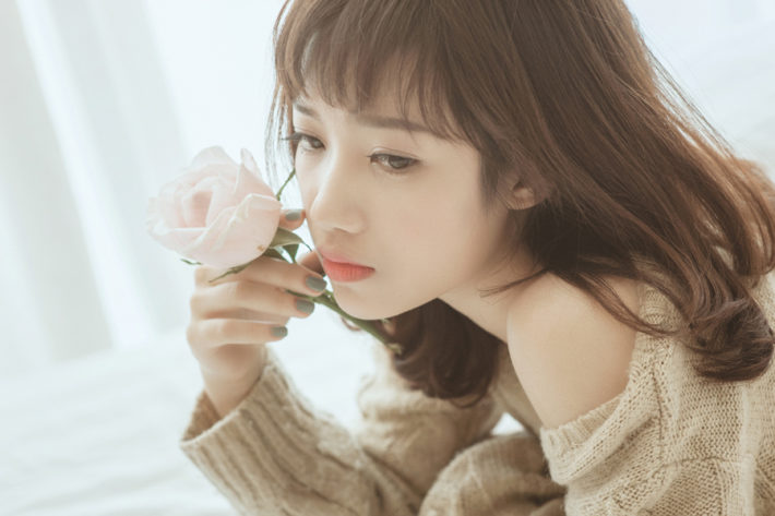 ピンクの花を頬に当てている女性