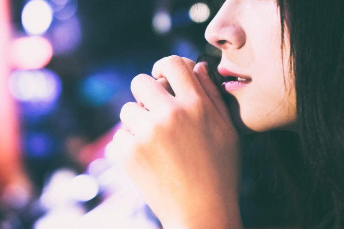 寂しげな女性の横顔と夜の街のネオン