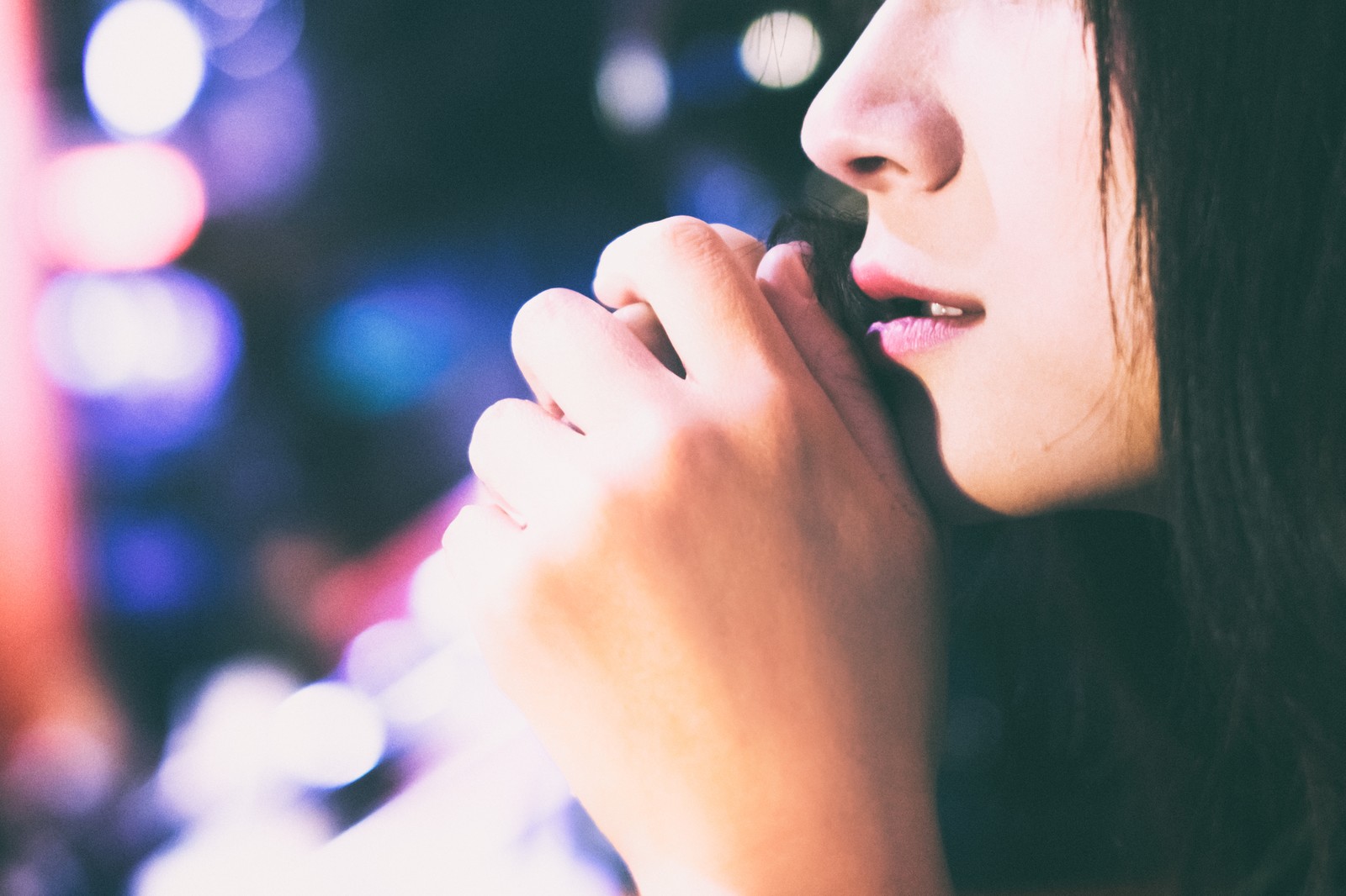 寂しげな女性の横顔と夜の街のネオン