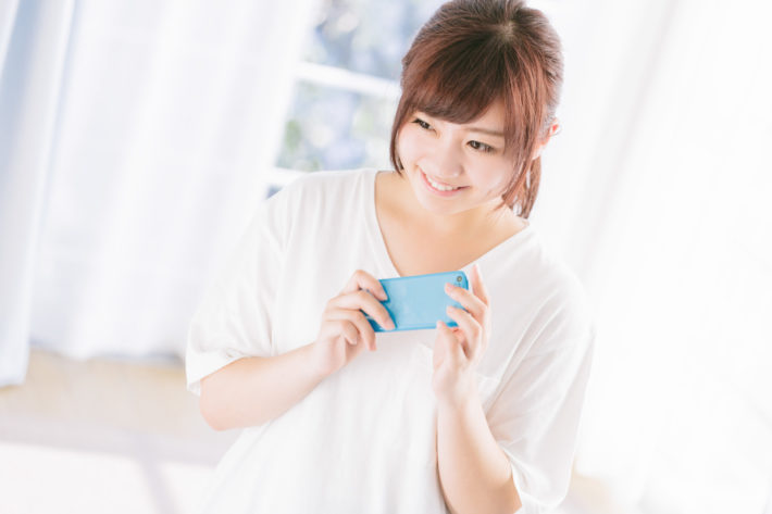 スマホを持って微笑んでいる女性