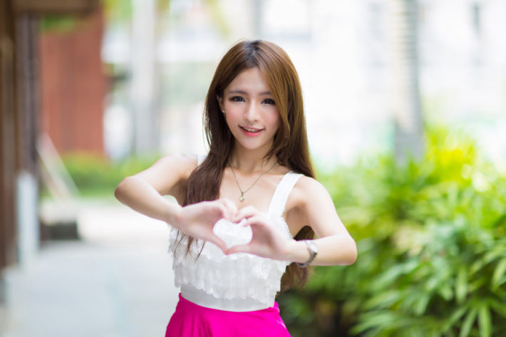 手でハートの形を作って微笑んでいる女性