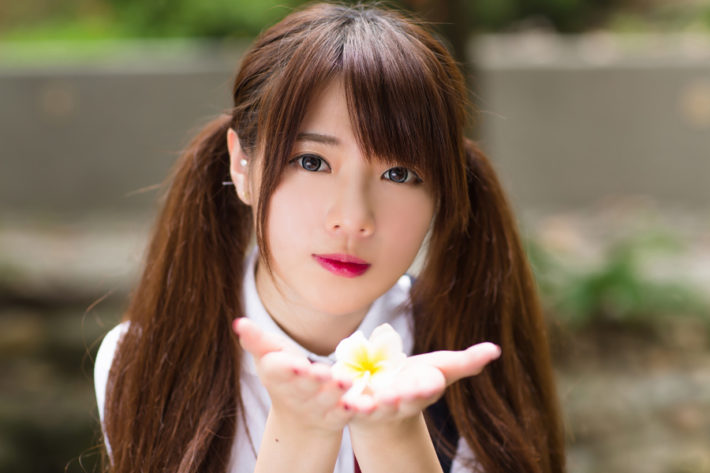 掌に花びらを乗せてコチラを見ている可愛いオタク女性