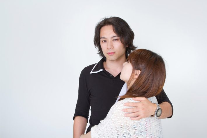 女性の肩に手を回し悪巧みしている顔の男性