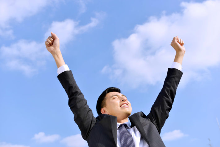 青空に向かって背伸びをしている男性