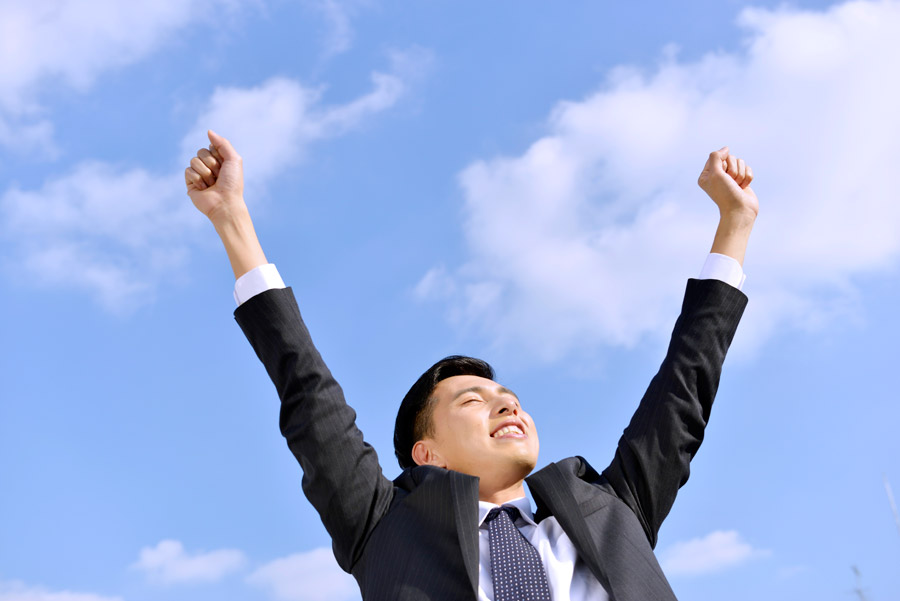 青空に向かって背伸びをしている男性