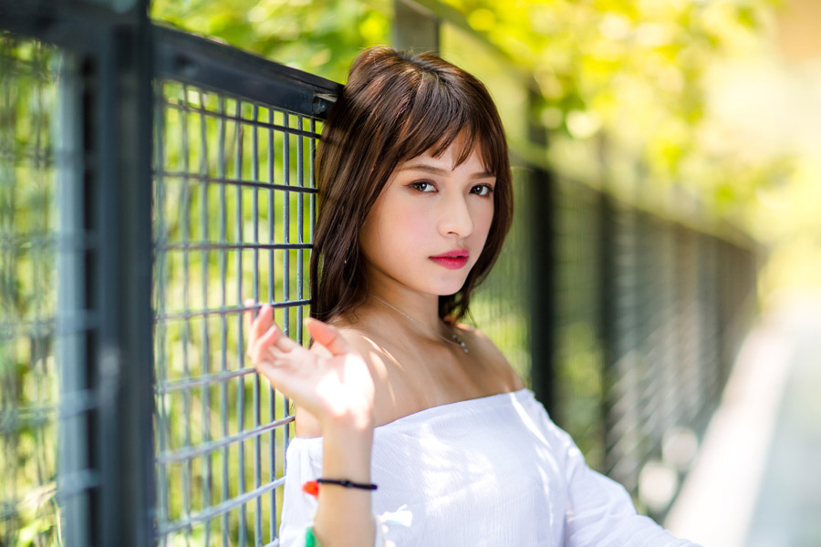 フェンスにもたれているオフショルダーの女性