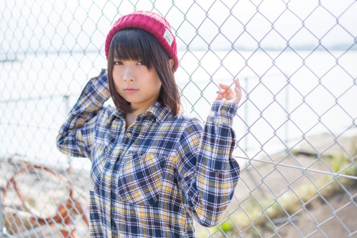 フェンスに持たれているネルシャツを着た女性