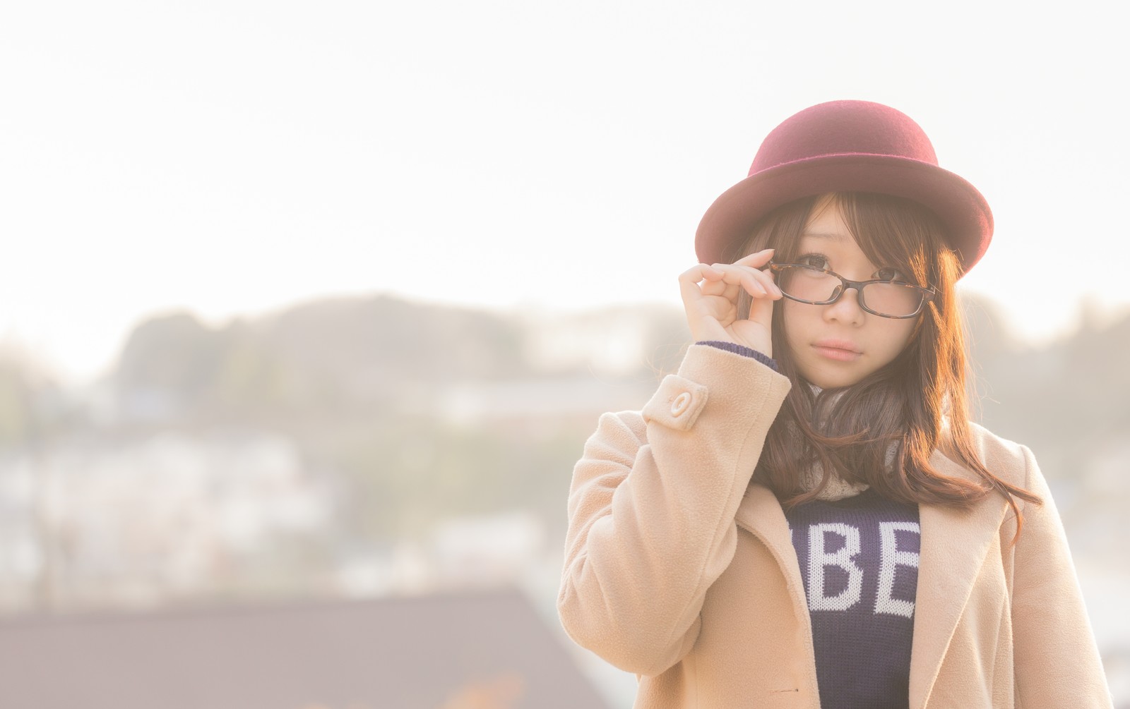 メガネの縁を持ちながらこちらを見つめている女性