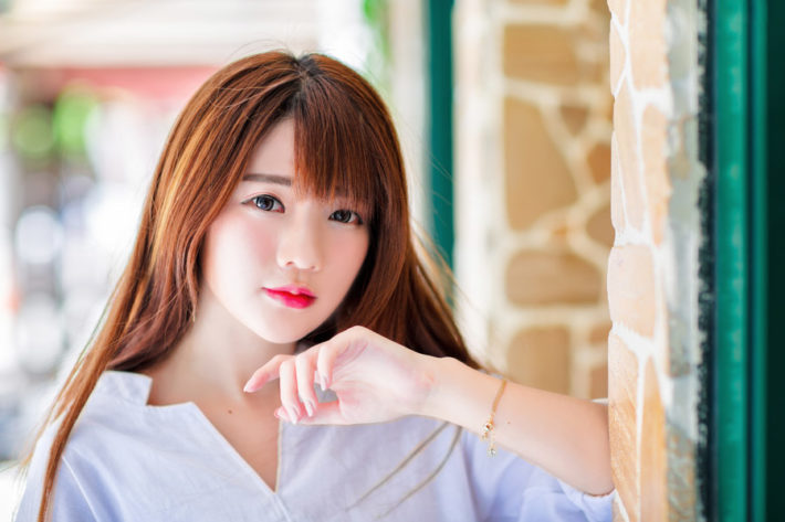 壁にもたれているブラウスを着た女性