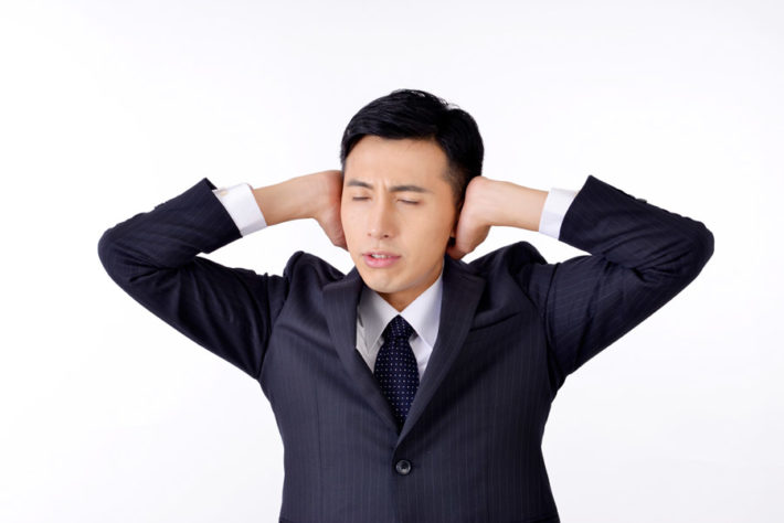 耳をふさいでいる男性