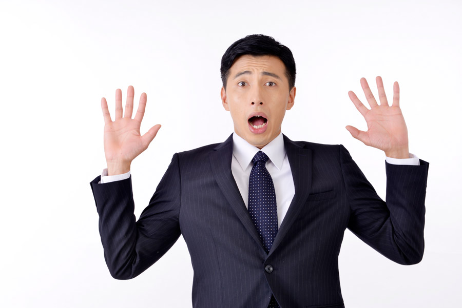 手を広げて驚くスーツ姿の男性