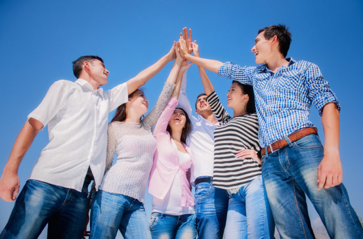 青空に手を掲げて掌を合わせている男女