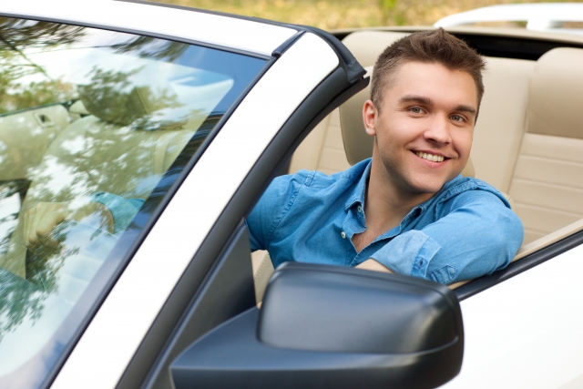 運転席に座っている笑顔のイケメン外国人男性