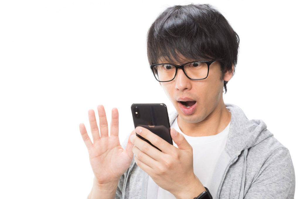 スマホを見て驚いている男性