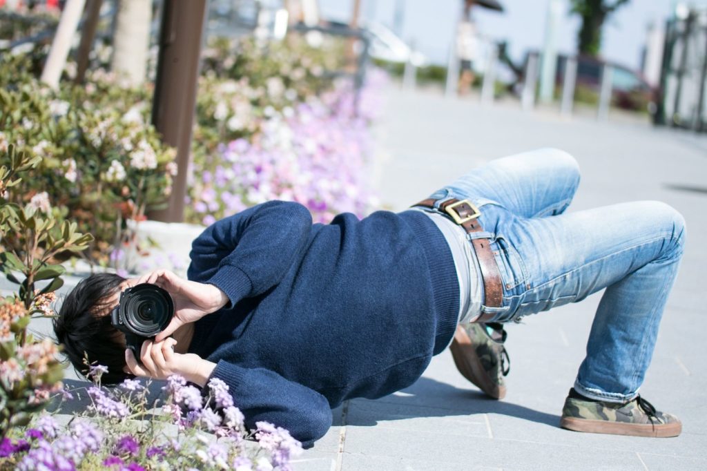 道端に寝そべって写真を撮っている男性