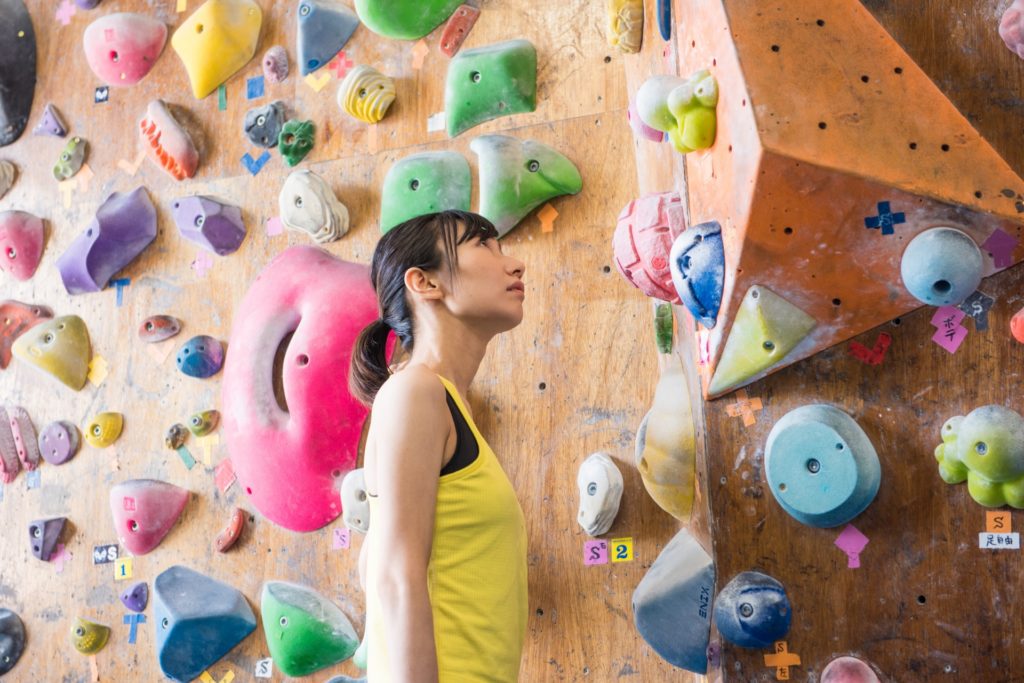 ボルダリングで壁を見つめている女性