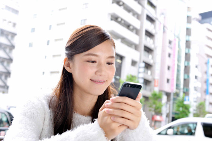スマホの画面を見ている美人女性