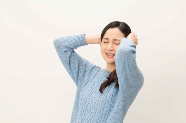 頭を抱え、しかめっ面の女性