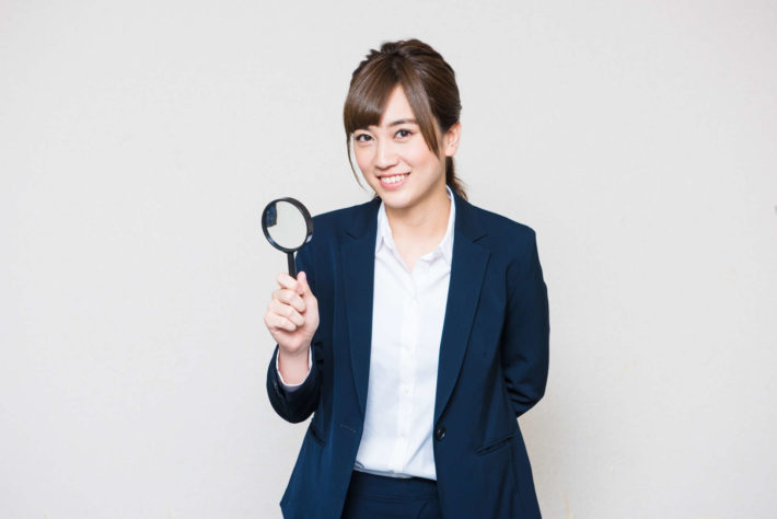 虫眼鏡を持っているオフィスレディ