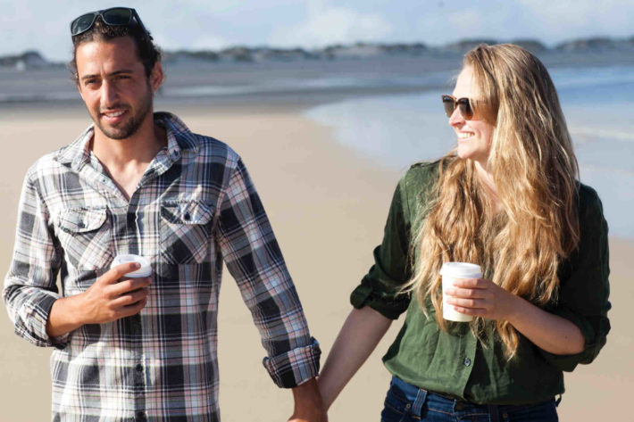 海辺を手をつないで歩くカップル