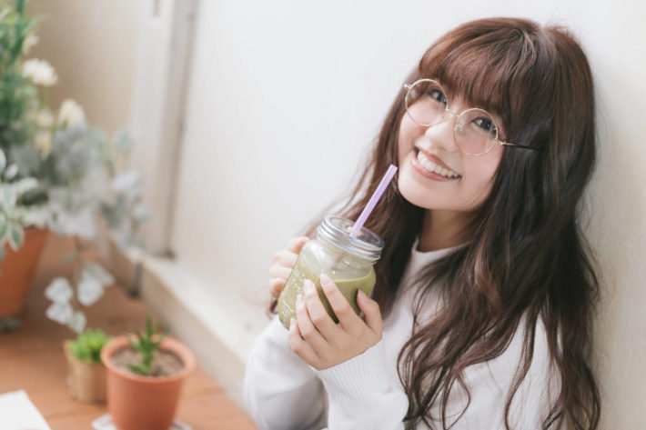 スムージーを飲んで微笑んでいるメガネ女子