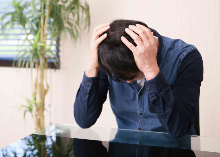 頭を抱えてうなだれている男性