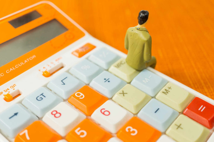 電卓の上に腰掛けている男性の人形の背中