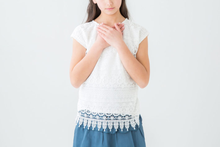 緊張して胸に手を当てている女性