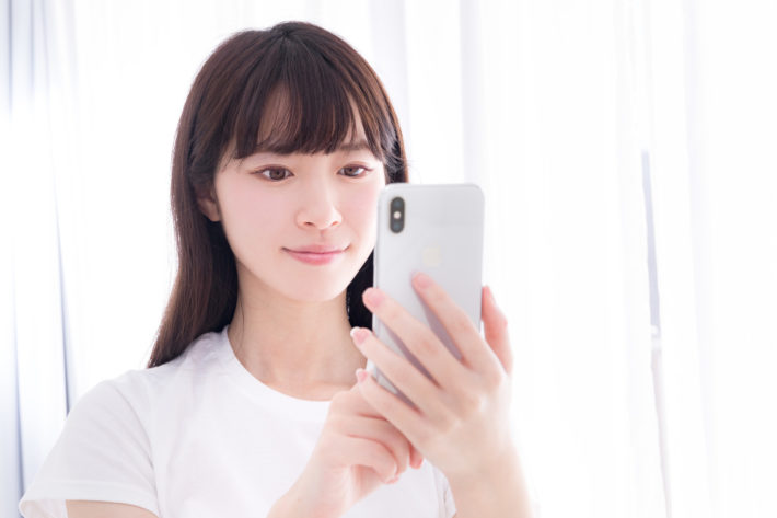 スマホを手に持ち笑顔の女性