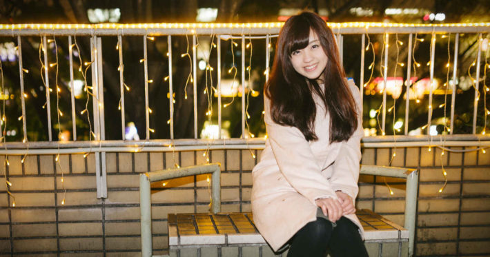 ベンチに座って微笑んでいるモテ女